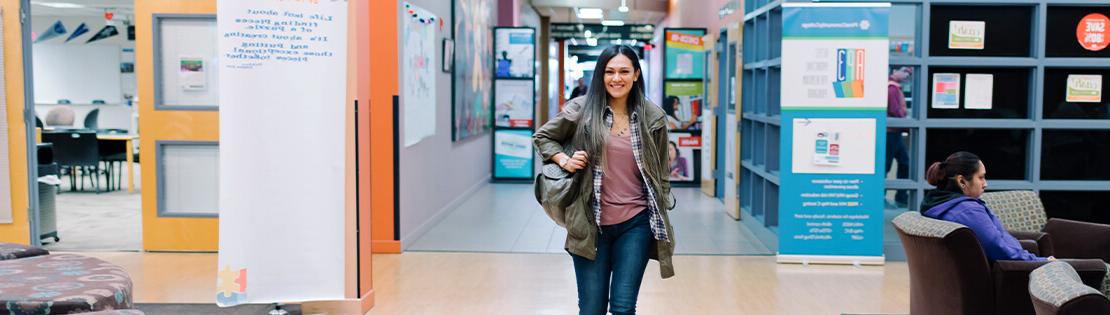 A student walks through the halls at Pima's Desert Vista Campus smiling